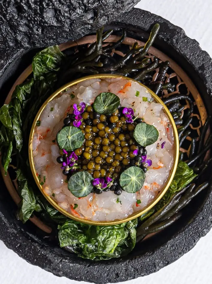 Caviar on a seafood tartare, served in a volcanic stone bowl