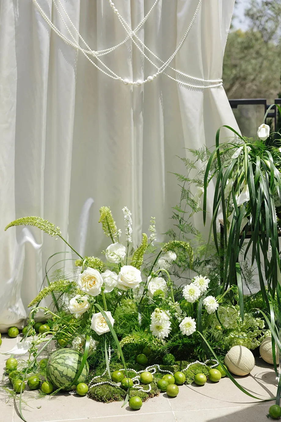 White flowers, greenery and limes arranged beneath a draped linen canopy