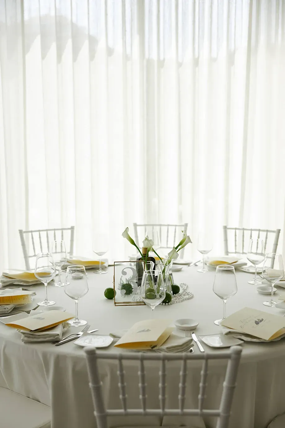 A round event table dressed in white with calla lilies and printed menus