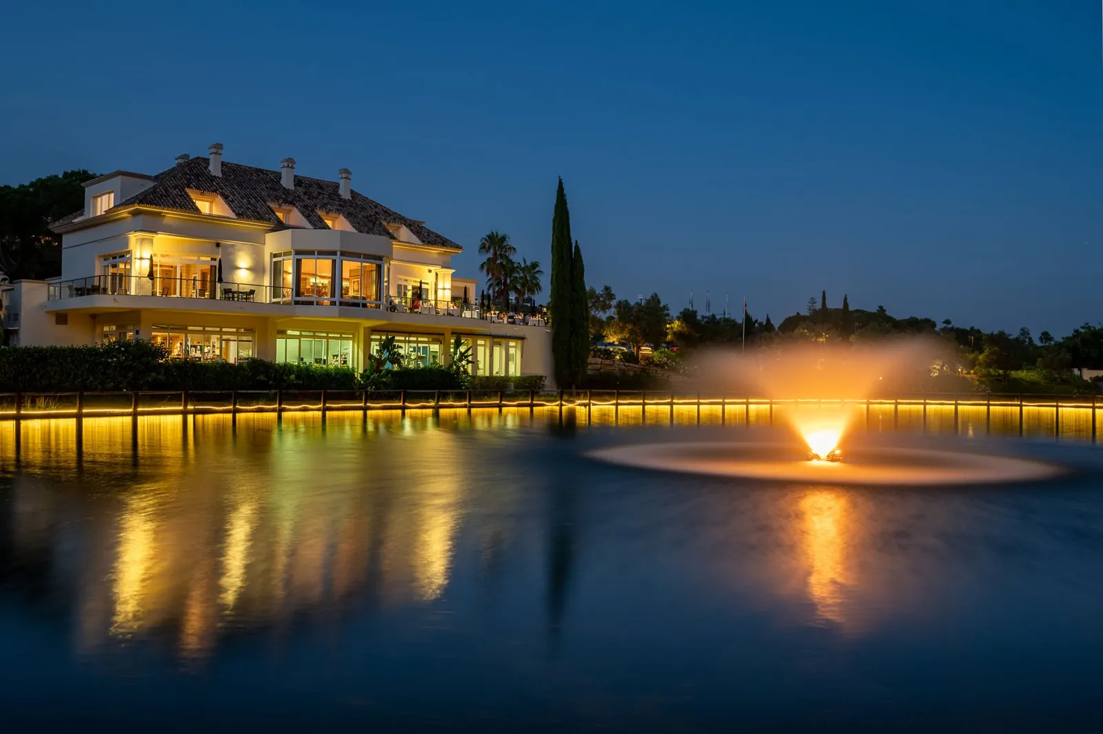The clubhouse and lake at night with the fountain lit