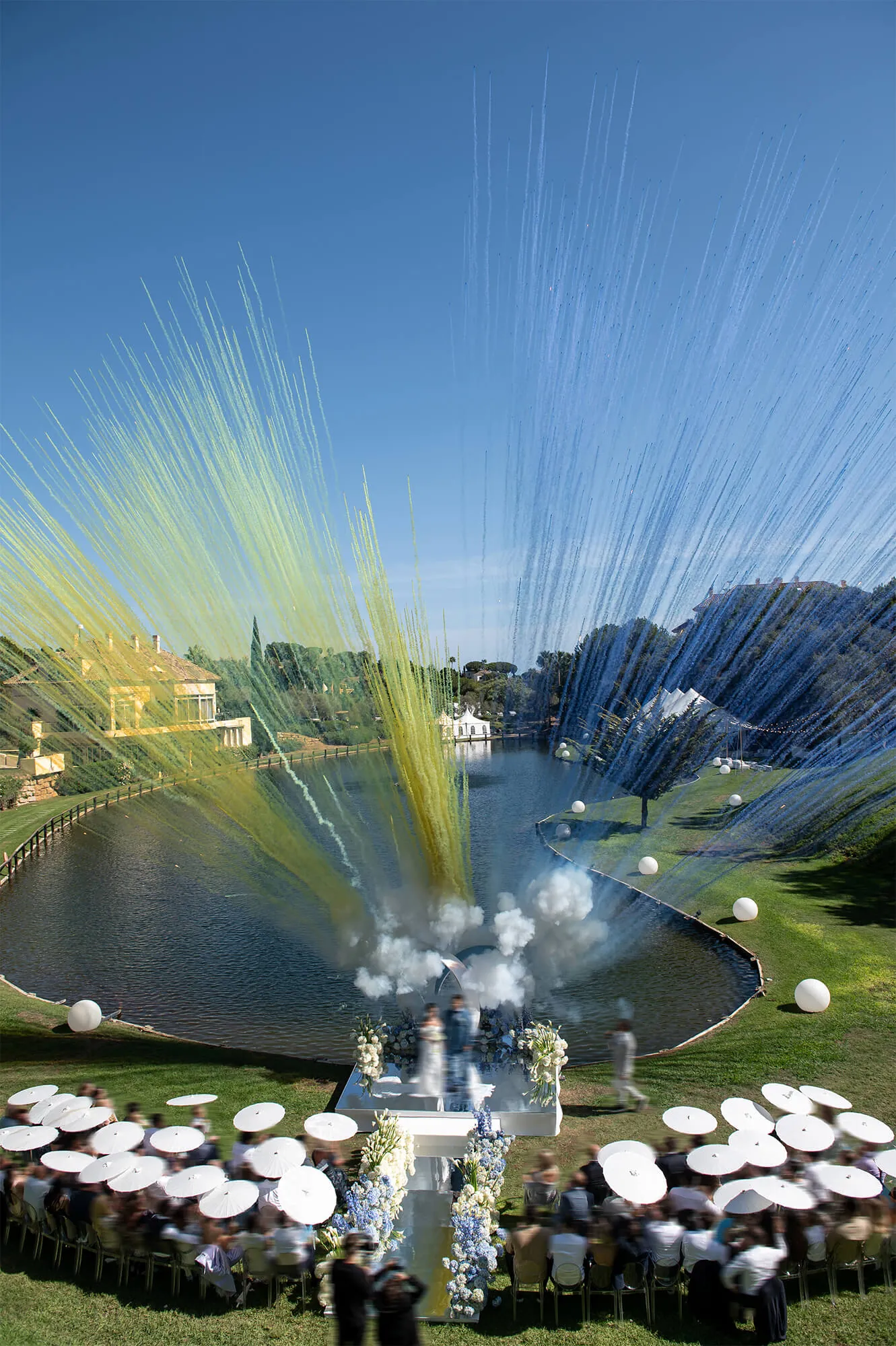 Aerial view of a wedding reception around the lake, with a confetti burst over the water